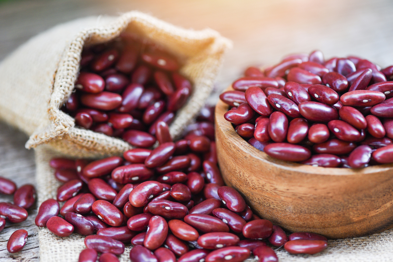 Red bean in wooden bowl on sack background / Grains red kidney beans /