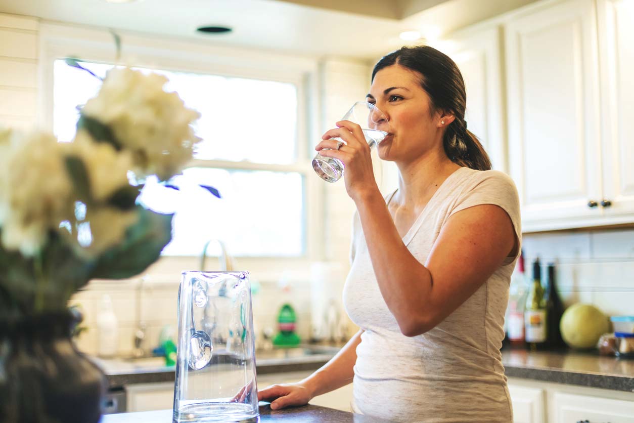 young woman drinking filtered water from glass