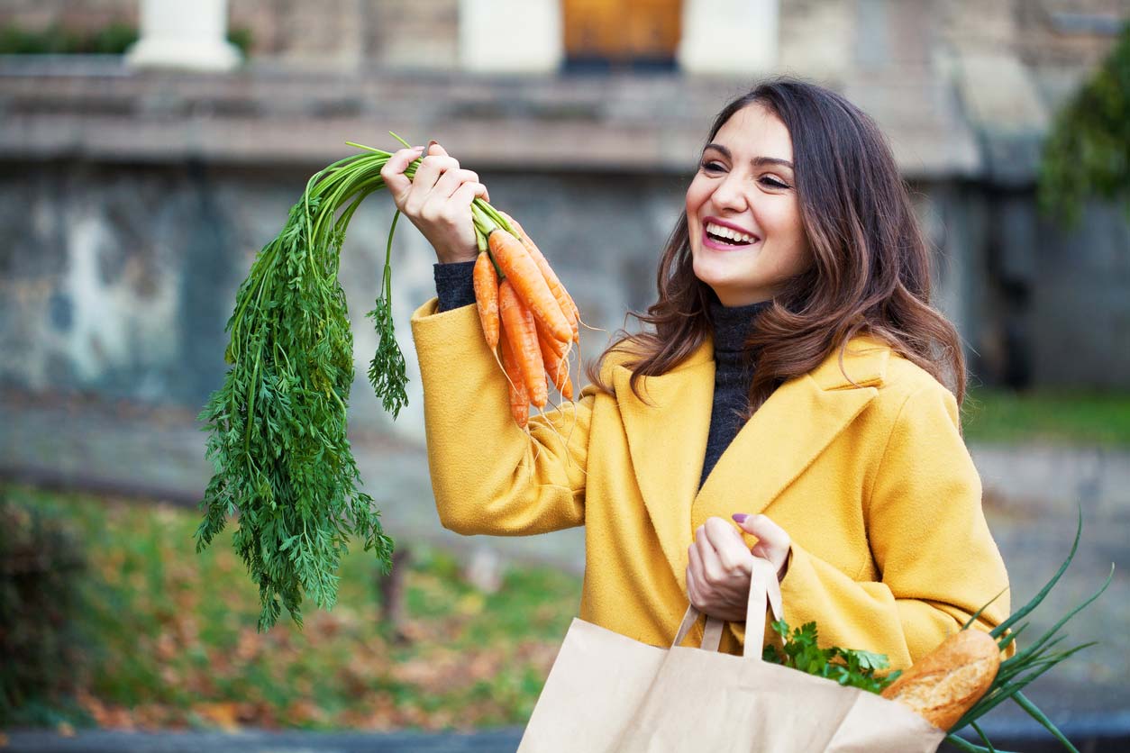 woman holding grocery bag and carrots