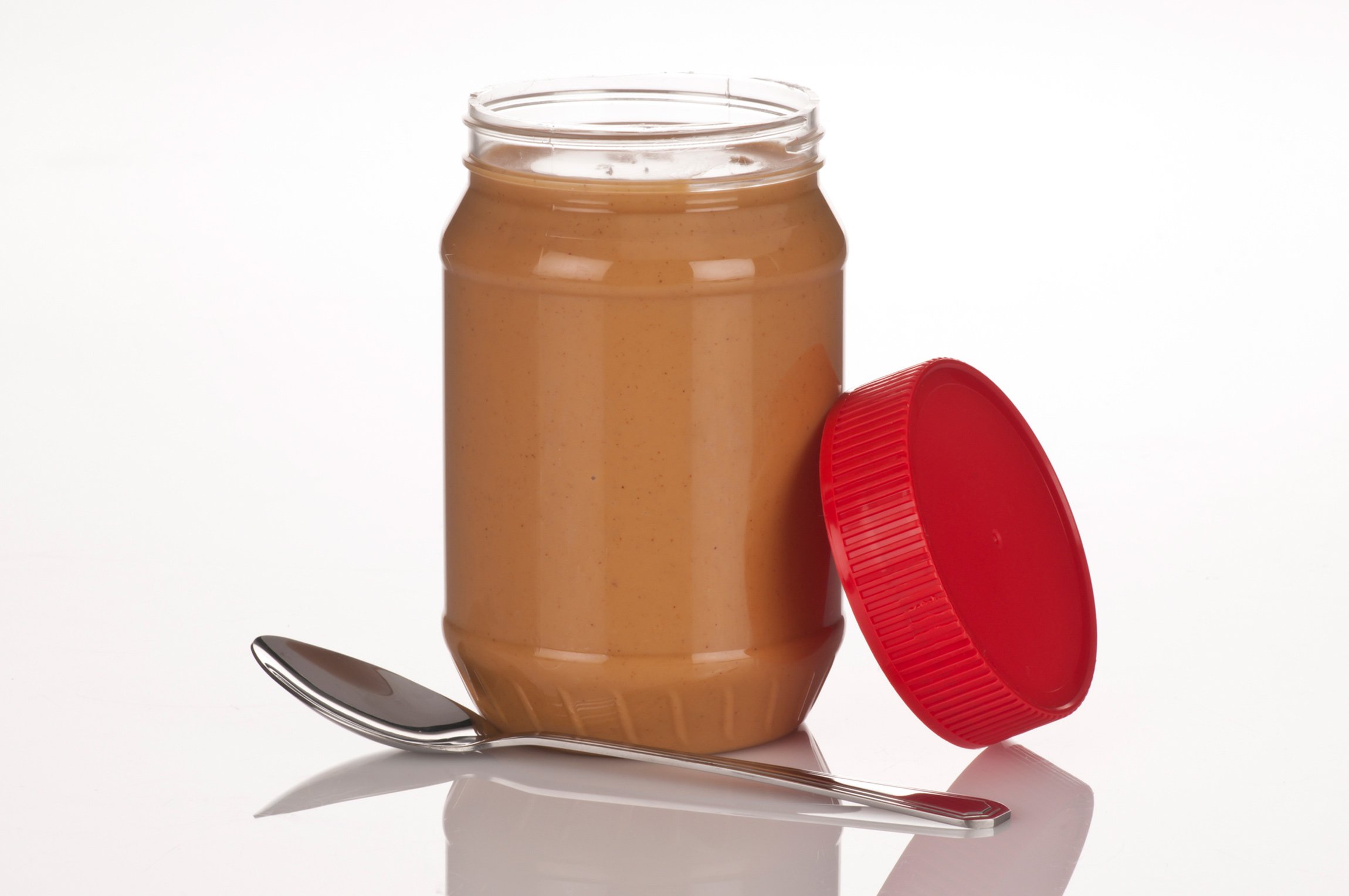 A jar of peanut butter with a spoon and the lid off