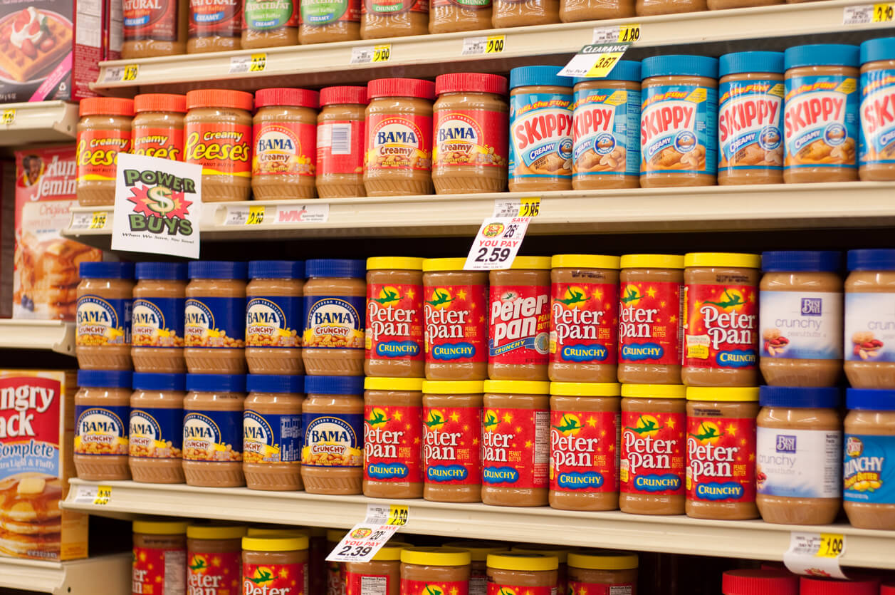 a variety of peanut butter and other nut butter on shelves in grocery store