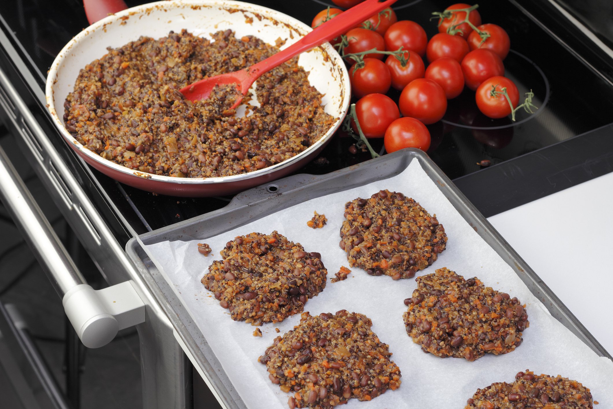 Parchment paper lined cookie sheet with quinoa and three bean veggie burgers ready to be cooked. Preparing tricolor bean and quinoa burgers recipe in the kitchen.